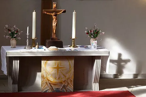 Altar mit Kerzen, 2 Blumensträußen und einem Kreuz